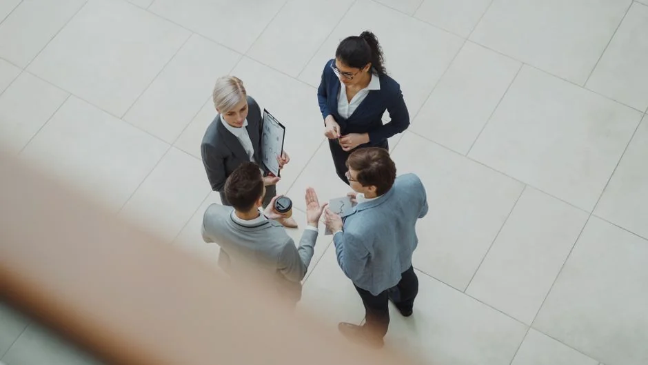 Two businessmen analyze stock market data using a smartphone and laptop in a modern office setting.